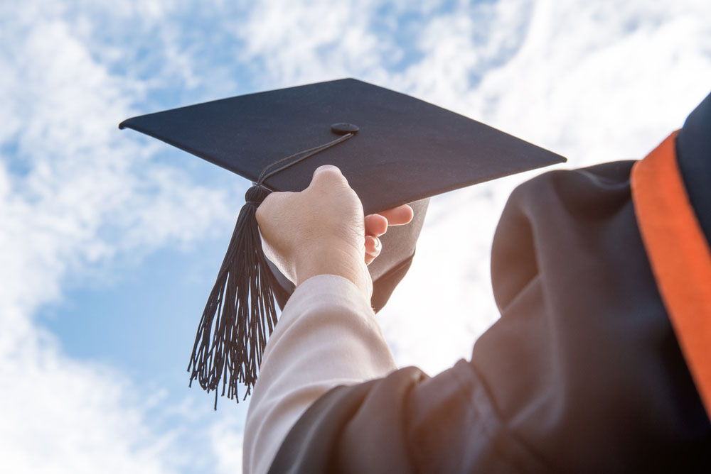 Un soñador sosteniendo un birrete de graduación.