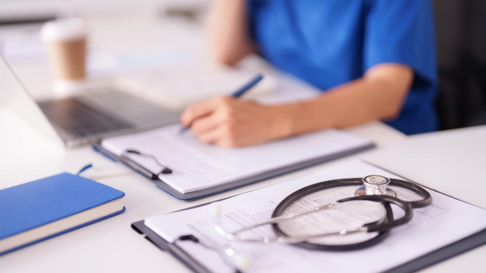 Entorno médico con estetoscopio, historiales médicos y portapapeles sobre el escritorio.